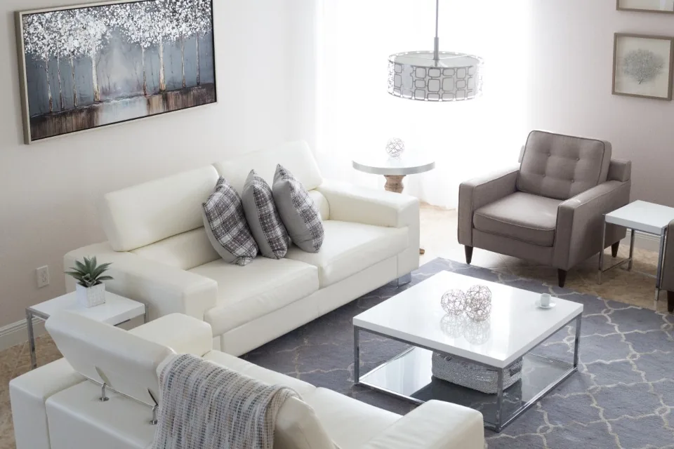 Salón con sofás blancos, sillón, mesa de centro y lámpara de techo