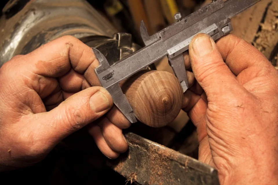 Manos midiendo una pieza de madera